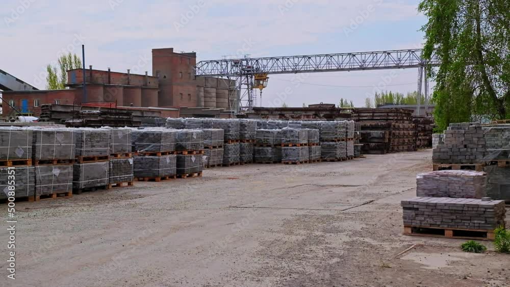 Industrial area with building materials stacked outside. Piles of grey bricks on wooden pallets at the backdrop of plant premises. Industrial area with building materials stacked outside. Piles of grey bricks on wooden pallets at the backdrop of plant premises.