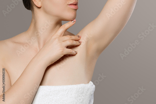 Skin care. Armpit epilation  laser hair removal. Young woman holding her arms up and showing clean underarms  depilation on smooth clear skin.