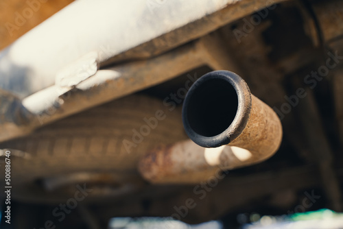 Rusty exhaust pipe with soot close-up. The spare tire is installed from below, the bottom of the car