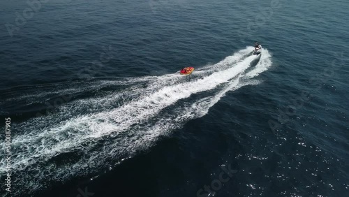 Wallpaper Mural Happy people are going to swim on an air mattress behind a jet ski. Tourists ride the inflatable watercraft boat. Sea attraction. Jet ski skating people on a large Inflatable raft. Aerial copter view. Torontodigital.ca