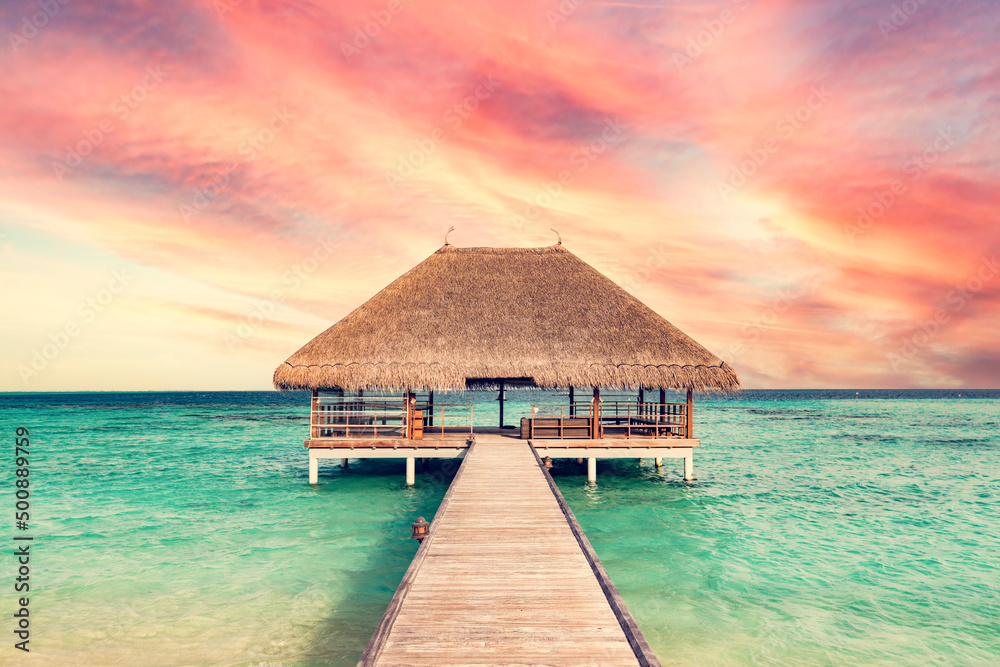 Beach in Maldives at sunset, wooden jetty