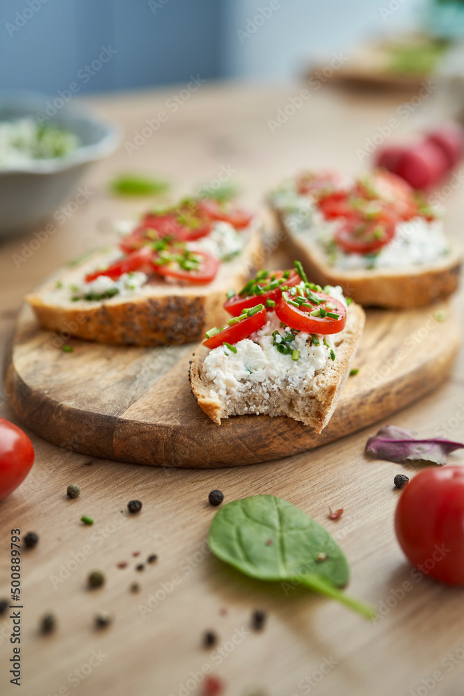 Close up of bitten sandwich with cottage cheese  on wooden board