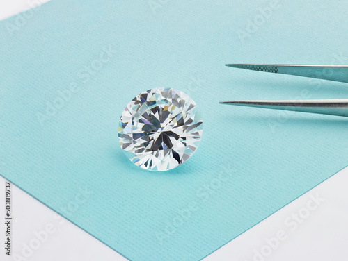 Loose Diamond on Tiffany Blue Coloured Background with Tweezers 