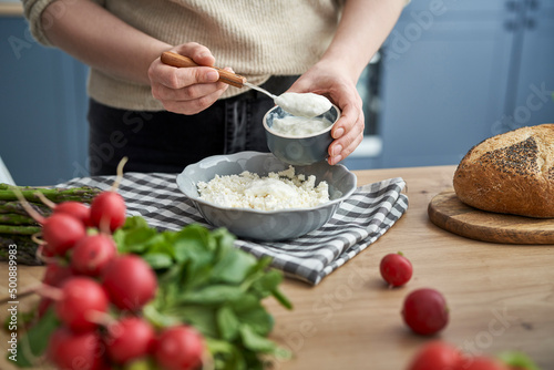 Woman adding yoghurt to cottage cheese for spring sandwiches