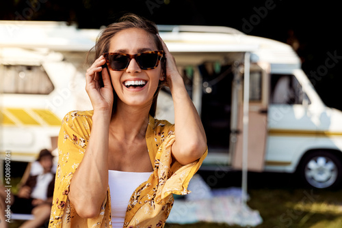 Portrait of young cheerful woman and camper car in the background Fototapet
