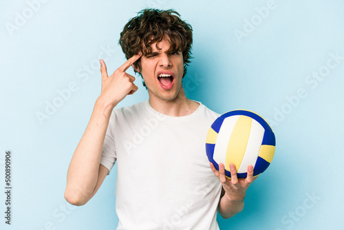 Young caucasian man playing volleyball isolated on blue background showing a disappointment gesture with forefinger.