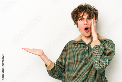 Young caucasian man isolated on white background impressed holding copy space on palm.