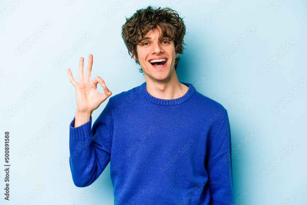 Young caucasian man isolated on blue background cheerful and confident showing ok gesture. Young caucasian man isolated on blue background cheerful and confident showing ok gesture.