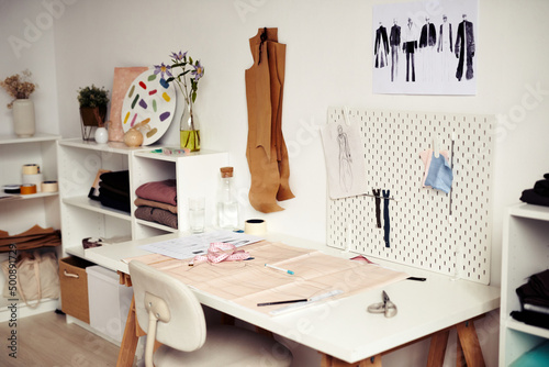 Paper with drawn sewing pattern and sketches on desk in fashion studio of designer