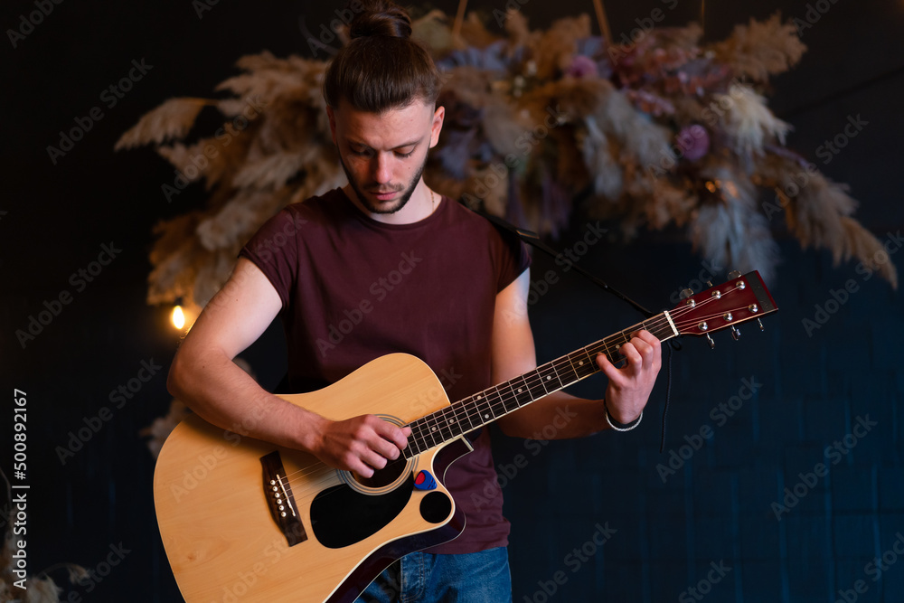 Obraz premium Male musician playing acoustic guitar. Guitarist plays classical guitar on stage in concert