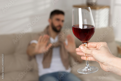 Man refusing to drink red wine indoors  closeup. Alcohol addiction