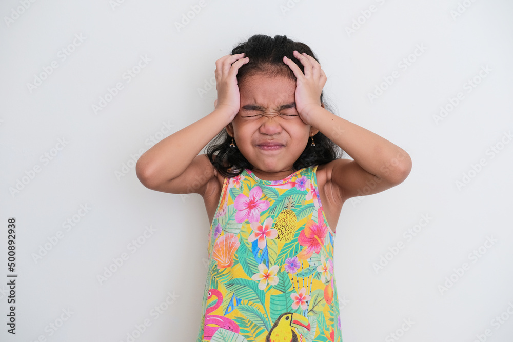 Asian kid girl showing stressed expression with both hand on her head Asian kid girl showing stressed expression with both hand on her head
