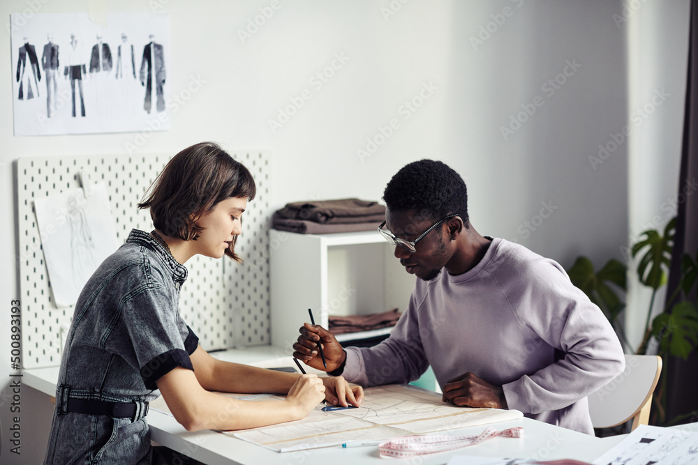 Diverse team of garment designers creating new sewing patterns for upcoming collection Diverse team of garment designers creating new sewing patterns for upcoming collection