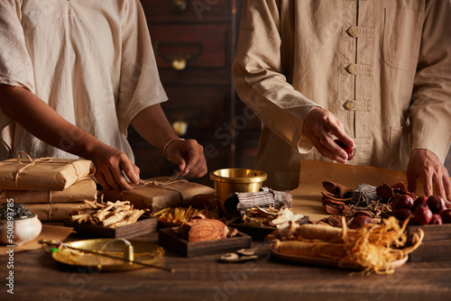 Fotografie Front view of apocathery is wrapping herb with chinese traditional medicine in w