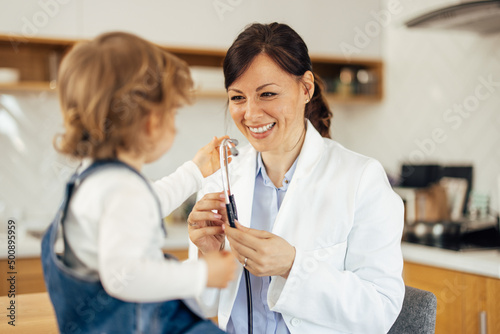 Home visit, a female pediatrician played with a cute toddler, sh photo