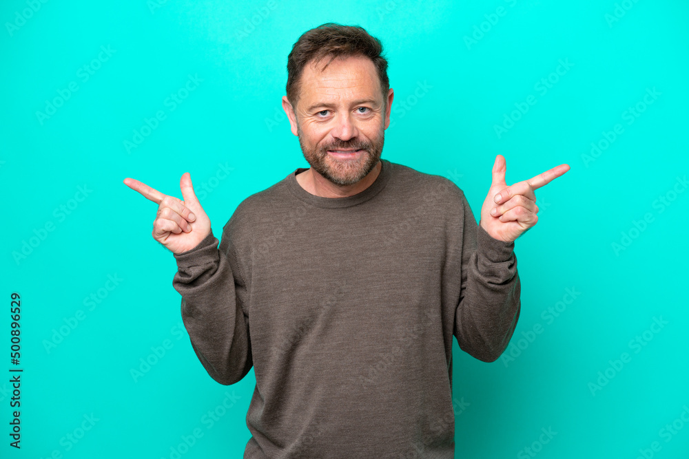 Middle age caucasian man isolated on blue background pointing finger to the laterals and happy