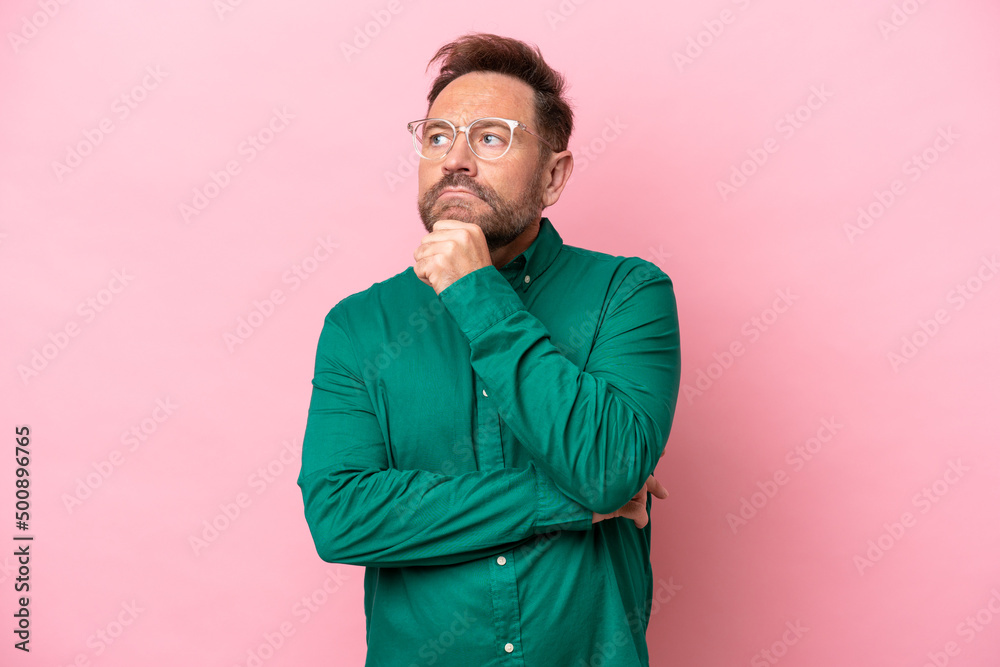 Middle age caucasian man isolated on pink background and looking up Middle age caucasian man isolated on pink background and looking up