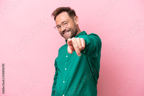 Middle age caucasian man isolated on pink background pointing front with happy expression