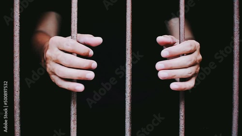 hand man hold steel in jail on black background.concept for prisoner,sadness,detain,erroneousness