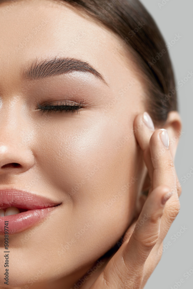 Obraz premium Closeup happy young woman applying cream to her face Skincare and cosmetics concept. Cosmetics. Woman face skin care.Natural makeup, touching face.