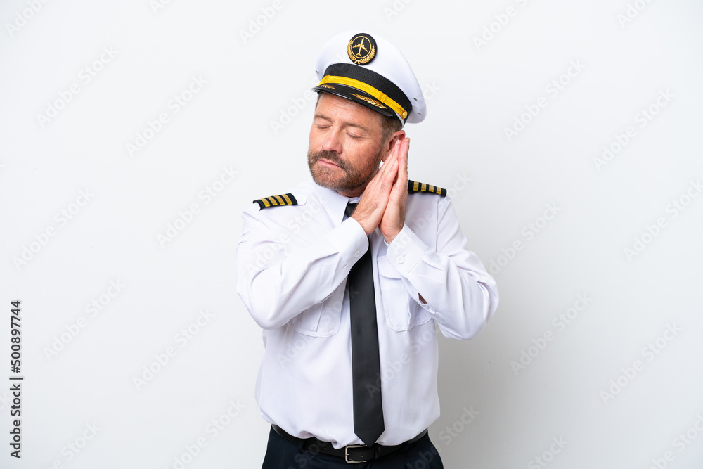 Airplane middle age pilot isolated on white background making sleep gesture in dorable expression Airplane middle age pilot isolated on white background making sleep gesture in dorable expression