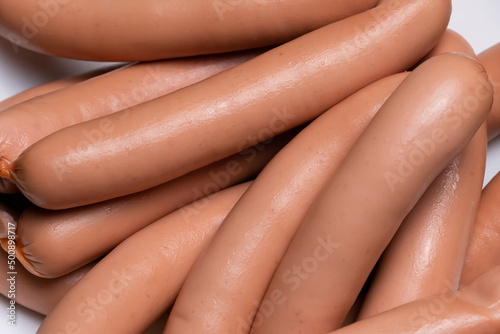 Photography Close-up of sausages for hot dogs made of raw chicken meat on a plate on a dark background