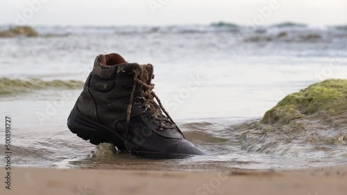 Abandoned shoe as a garbage on a sangy beach in Sicily, Italy with slight slow-motion effect
