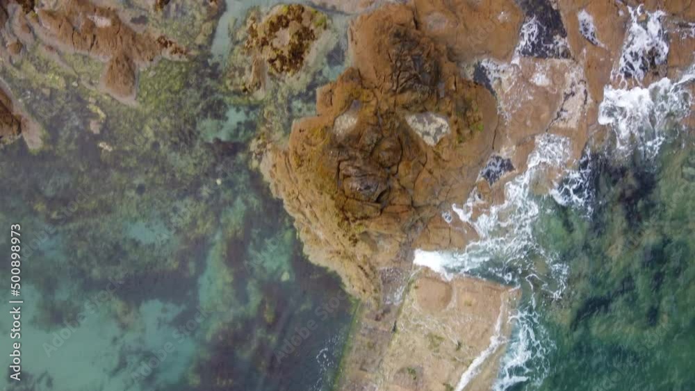 Aerial top-down forward over waves breaking on rocky coast of Saint-Malo in Brittany, France Aerial top-down forward over waves breaking on rocky coast of Saint-Malo in Brittany, France