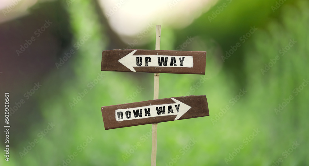 Up way-Down way on a wooden signpost on a natural green background.copy space.