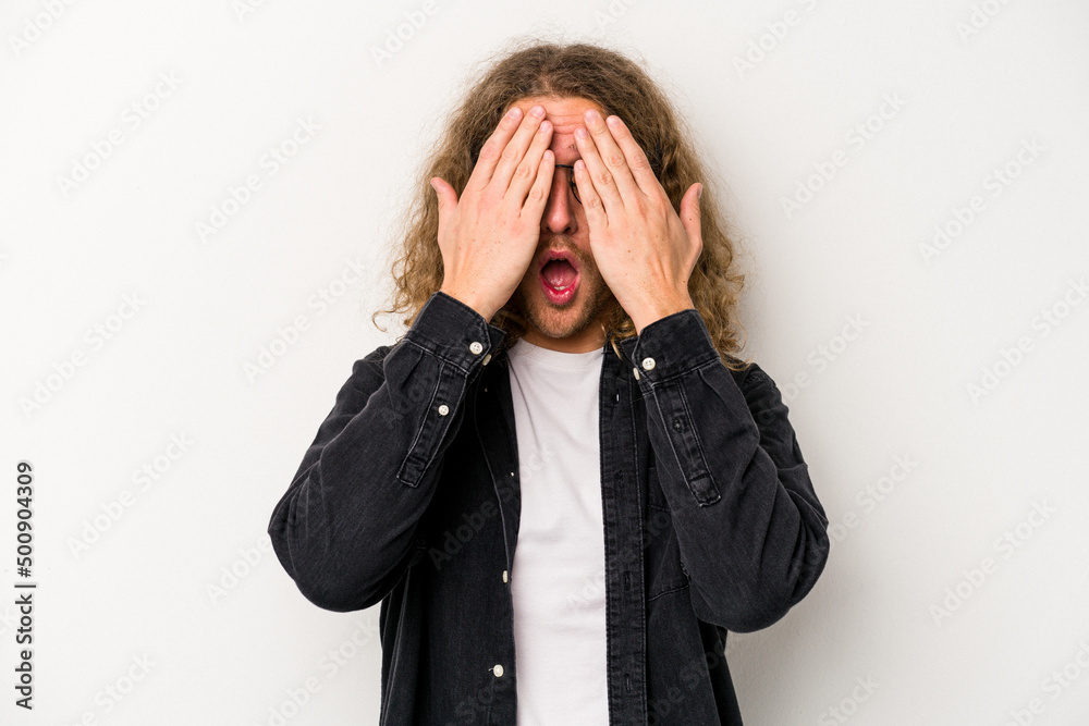 Young caucasian man isolated on white background having fun covering half of face with palm. Young caucasian man isolated on white background having fun covering half of face with palm.