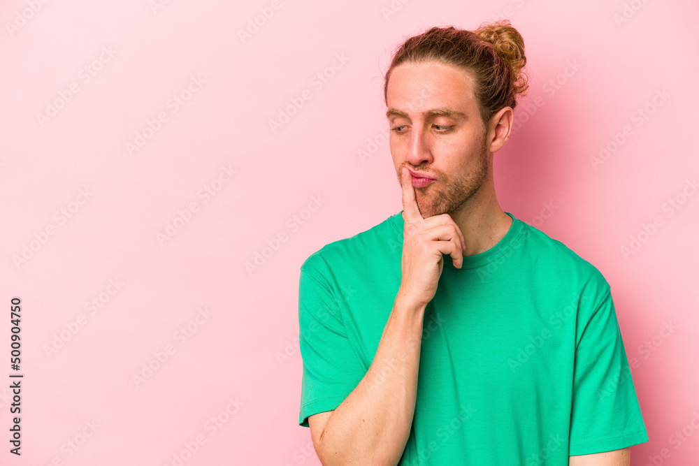 Young caucasian man isolated on pink background looking sideways with doubtful and skeptical expression. Young caucasian man isolated on pink background looking sideways with doubtful and skeptical expression.