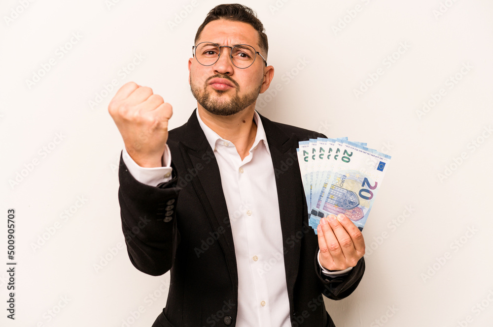 Business hispanic man holding banknotes isolated on white background showing fist to camera, aggressive facial expression. Business hispanic man holding banknotes isolated on white background showing fist to camera, aggressive facial expression.