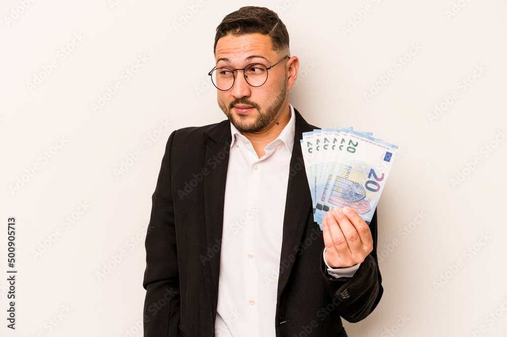 Business hispanic man holding banknotes isolated on white background confused, feels doubtful and unsure. Business hispanic man holding banknotes isolated on white background confused, feels doubtful and unsure.