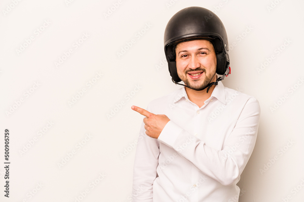 Hispanic business man going to work with motorcycle isolated on white background smiling and pointing aside, showing something at blank space. Hispanic business man going to work with motorcycle isolated on white background smiling and pointing aside, showing something at blank space.