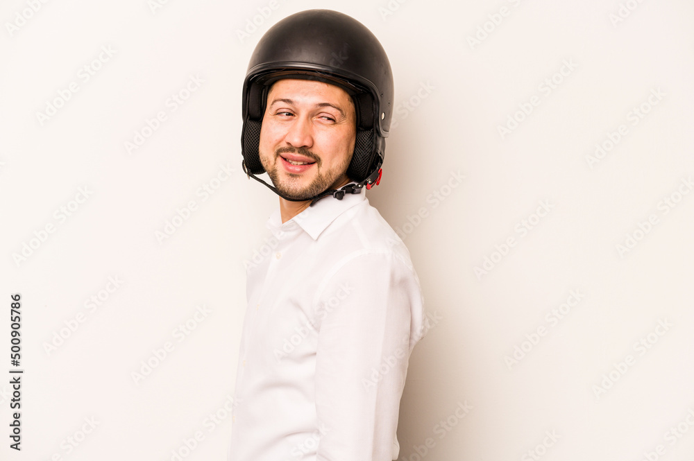 Hispanic business man going to work with motorcycle isolated on white background looks aside smiling, cheerful and pleasant. Hispanic business man going to work with motorcycle isolated on white background looks aside smiling, cheerful and pleasant.