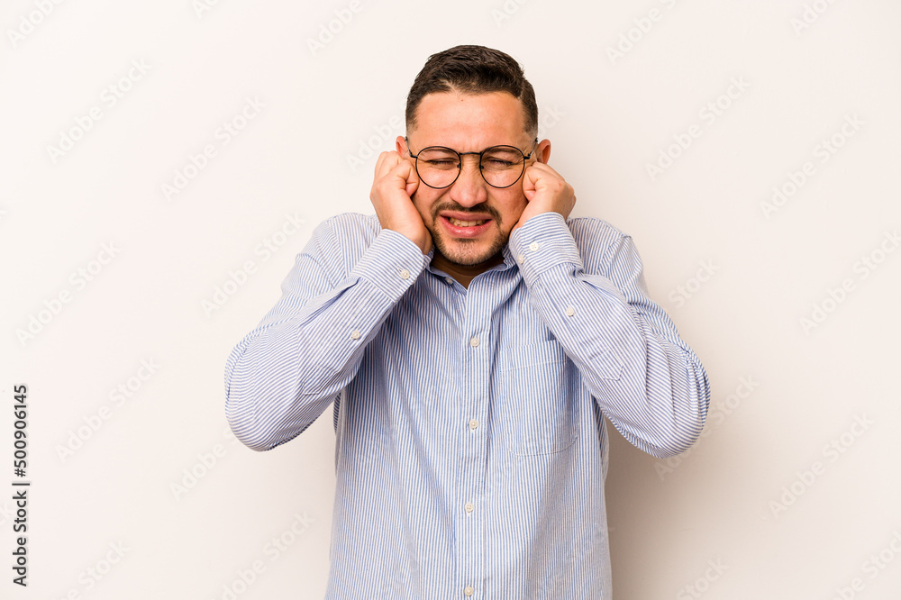 Young hispanic man isolated on white background covering ears with hands. Young hispanic man isolated on white background covering ears with hands.
