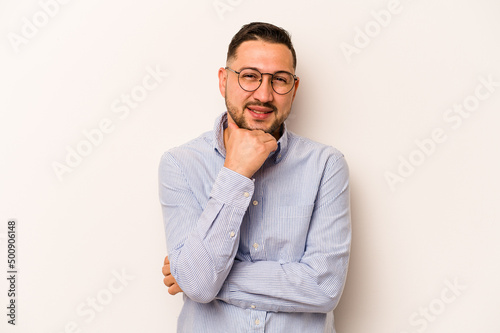 Young hispanic man isolated on white background smiling happy and confident, touching chin with hand.