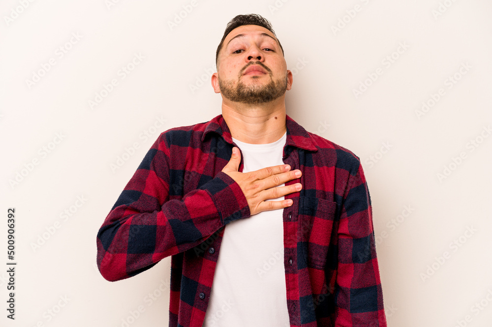 Young hispanic man isolated on white background taking an oath, putting hand on chest. Young hispanic man isolated on white background taking an oath, putting hand on chest.