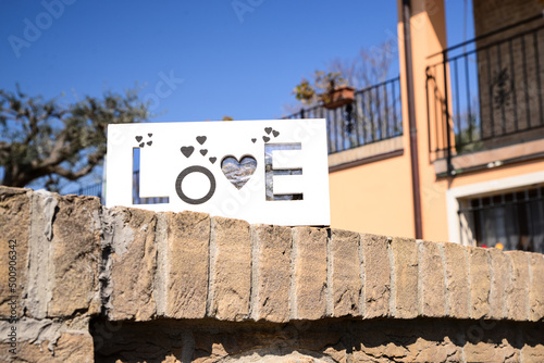 Board with word LOVE on brick fence outdoors