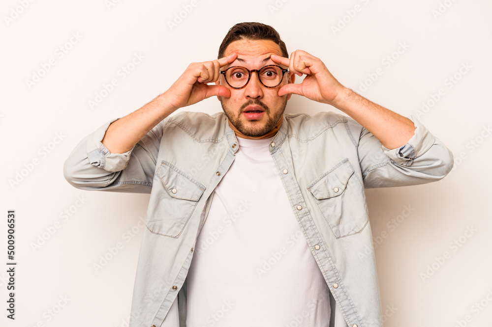 Young hispanic man isolated on white background keeping eyes opened to find a success opportunity.