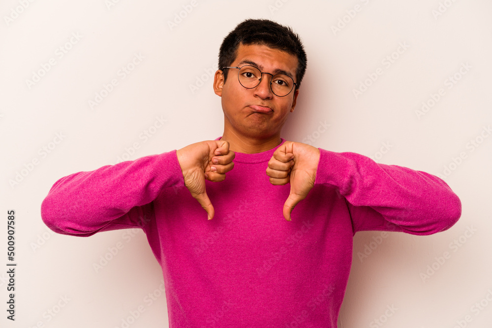 Young hispanic man isolated on white background showing a dislike gesture, thumbs down. Disagreement concept. Young hispanic man isolated on white background showing a dislike gesture, thumbs down. Disagreement concept.
