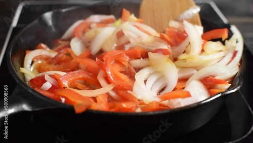 vegetables (onion and bell pepper) are fried in a frying pan