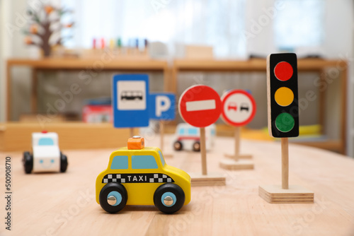 Different miniature road signs and cars on wooden table. Montessori toy