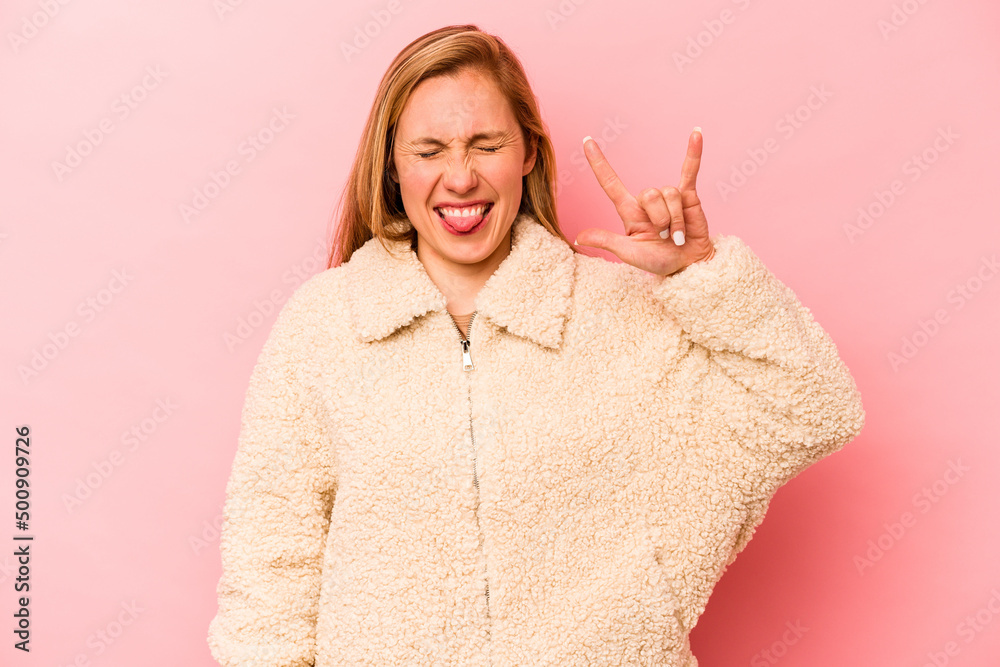 Young caucasian woman isolated on pink background showing rock gesture with fingers Young caucasian woman isolated on pink background showing rock gesture with fingers