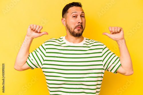 Young hispanic man isolated on yellow background feels proud and self confident, example to follow.