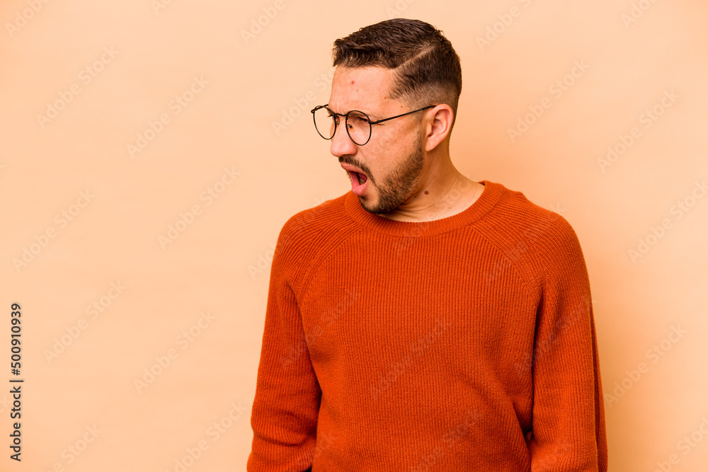 Young hispanic man isolated on beige background shouting very angry, rage concept, frustrated. Young hispanic man isolated on beige background shouting very angry, rage concept, frustrated.
