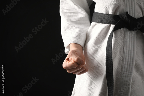 Εκτύπωση καμβά Man wearing keikogi and black belt on dark background, closeup view with space for text
