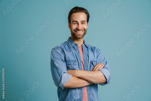 Fototapeta Young bristle man wearing shirt smiling while posing with arms crossed