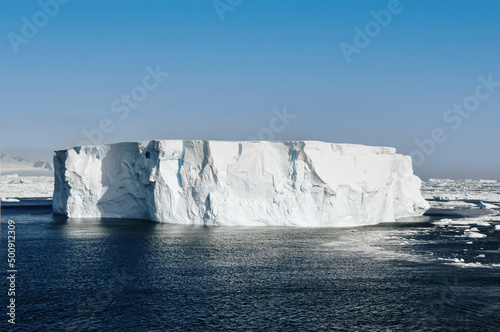 large iceberg near antarctic peninsula against blue sky
