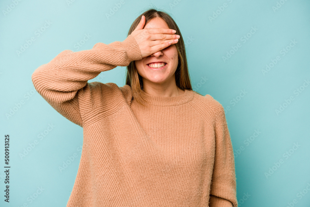 Young caucasian woman isolated on blue background covers eyes with hands, smiles broadly waiting for a surprise.